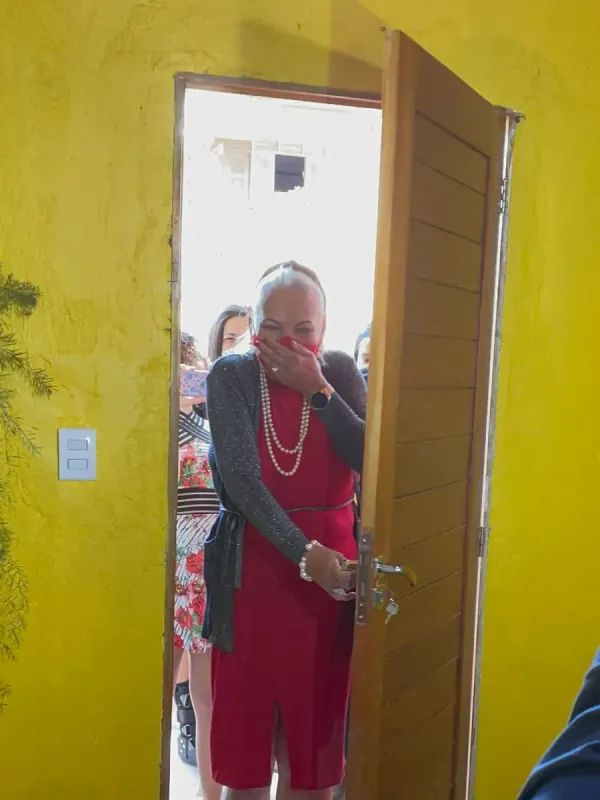 Dona Raimunda, emocionada, abrindo a porta da casa reformada pela ReforAMAR