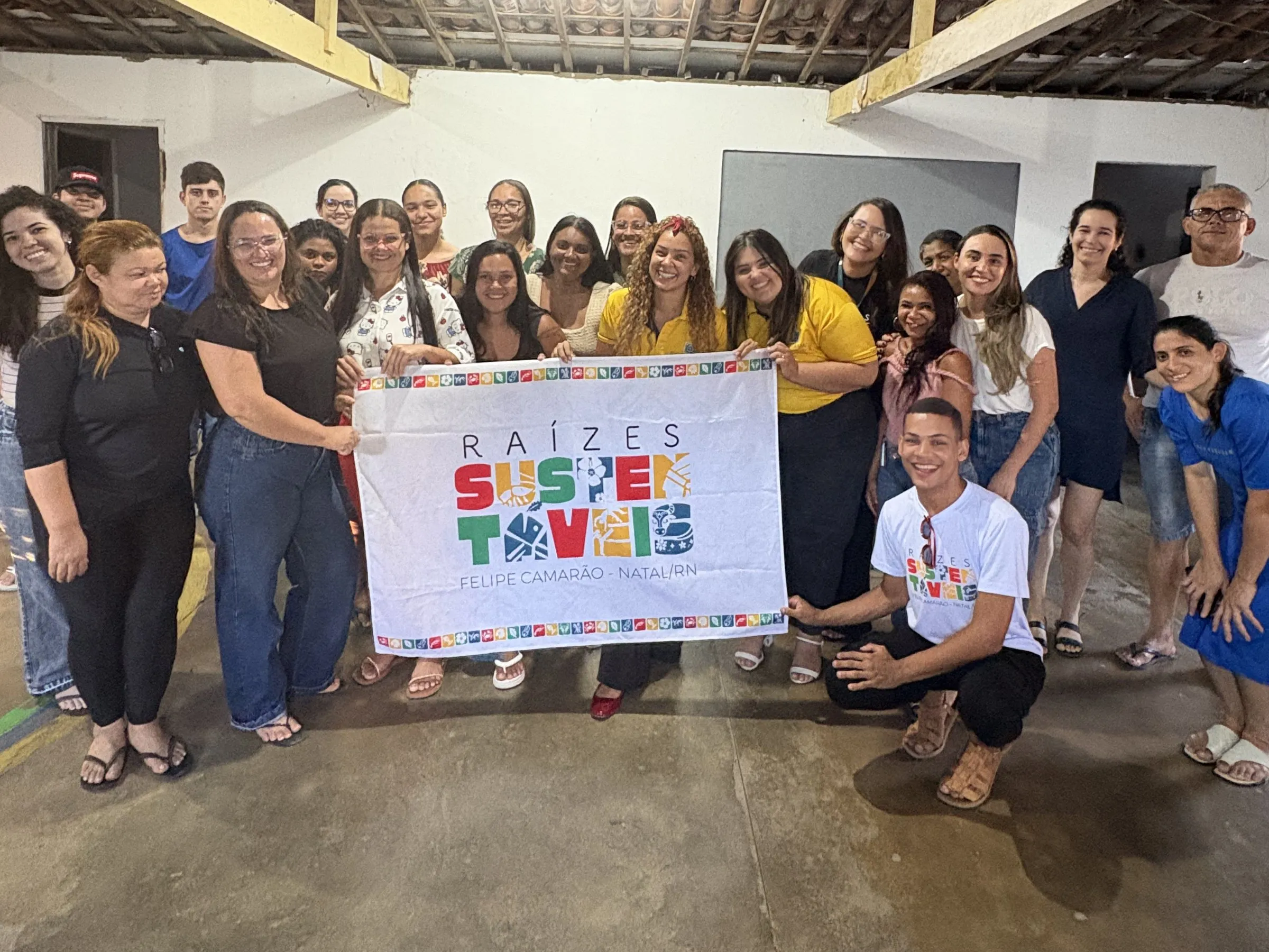 Participantes do projeto Raízes Sustentáveis em Felipe Camarão reunidos com a faixa do projeto